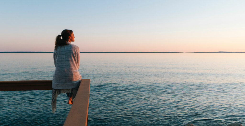 Frau, die am Meer in die Ferne blickt